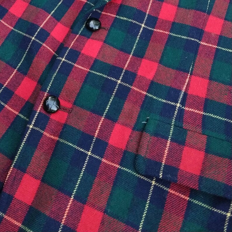 May include: Red, green, and black plaid fabric with two black buttons.