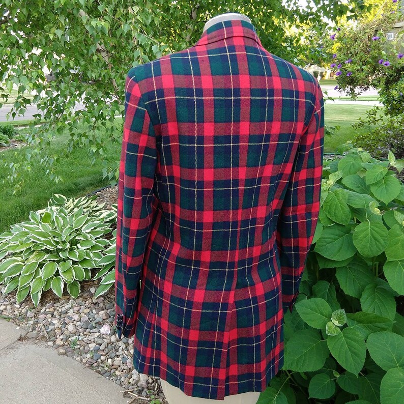 May include: A red, green, and yellow plaid blazer. The blazer has a single button closure and a notched lapel.