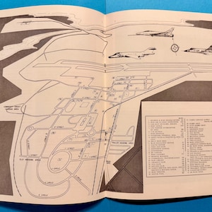 May include: An open book with a black and white map of an air force base. The map includes streets, buildings, and aircraft illustrations. A list of locations is on the right side of the page. The map is on a light beige background.