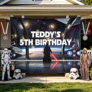 May include: A large rectangular backdrop featuring a space scene with a dark-cloaked figure holding a red lightsaber, text reading TEDDY'S 5TH BIRTHDAY, two white stormtrooper cutouts, two stormtrooper helmets, and two hanging lightsaber ornaments.