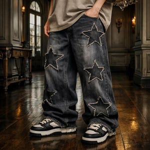 Puede incluir: Vaqueros de mezclilla de lavado oscuro con grandes recortes de estrellas y bordes deshilachados. Los vaqueros tienen un corte de pierna ancha y se combinan con zapatillas deportivas en blanco y negro. El estilo es casual y moderno.