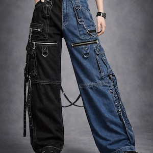 Könnte beinhalten: Zweifarbige Cargo-Jeanshose, vertikal geteilt, eine Seite schwarz und die andere blau. Merkmale sind mehrere Taschen mit Reißverschlüssen, Metallringen und Riemen. Die Hose hat ein weites Bein und wird mit schwarzen Plateauschuhen getragen.