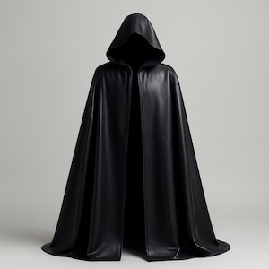Op de afbeelding: Een lange, zwarte cape met capuchon. De cape is gemaakt van een gladde, donkere stof en heeft een diepe capuchon. De voorkant van de cape is open. Het kledingstuk is ontworpen om te draperen en te stromen, waardoor een dramatisch silhouet ontstaat.