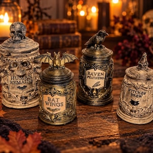 May include: Four decorative apothecary jars with lids, featuring ornate detailing and labels. The jars are labeled Human Remains, Bat Wings, Raven Feathers, and Witches Brew, with sculpted toppers including a skull, a bat, and a raven.