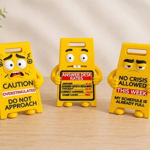 May include: Three yellow plastic caution signs with cartoon faces and arms. The left sign reads CAUTION OVERSTIMULATED DO NOT APPROACH. The center sign reads ANSWER DESK RATES with a price list. The right sign reads NO CRISIS ALLOWED THIS WEEK.