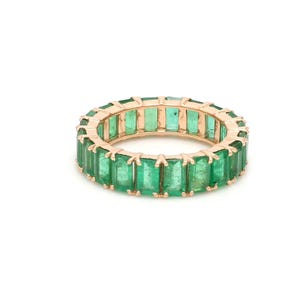 Op de afbeelding: Een roségouden eternity ring met smaragdgroene edelstenen. De ring heeft een warme roségouden band en de edelstenen zijn dicht op elkaar gezet, waardoor een doorlopende lijn van levendig groen ontstaat.