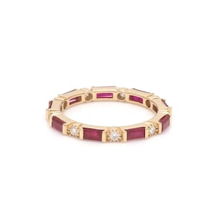 May include: A gold ring featuring alternating rectangular rubies and small round diamonds. The ring has a continuous design of gemstones set in a gold band, creating a sparkling and elegant look. The ring is set against a white background.