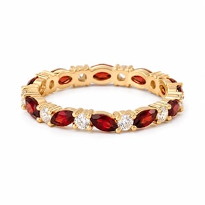 May include: A gold eternity band featuring an alternating pattern of marquise-cut deep red garnet gemstones and round-cut clear white diamonds. The stones are set in a continuous metal frame, creating a circular ring design with a polished finish.