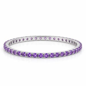 May include: A thin, circular eternity ring crafted from polished silver-toned metal. The band is set with a continuous row of small, round-cut, vibrant purple amethyst gemstones that span the entire circumference of the jewelry piece.
