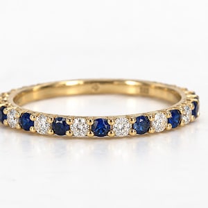 Peut inclure: Une alliance en or jaune ornée d'un motif alterné de saphirs bleus et de diamants blancs ronds, sertis en une rangée continue tout autour de la circonférence de cet anneau en métal fin.