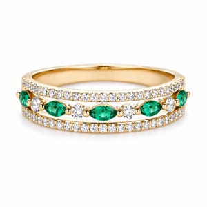 Puede incluir: Un anillo de oro con tres bandas. Las bandas superior e inferior están forradas con pequeños diamantes blancos. La banda central presenta piedras de esmeralda y diamantes blancos alternas. El anillo tiene un acabado brillante y pulido.