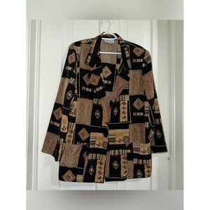 May include: A long-sleeve blazer featuring a patchwork-style pattern in shades of black, tan, and brown. The garment has a notched lapel, a single-button front closure, and two large patch pockets on the lower front. The fabric displays geometric shapes.