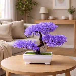 May include: A decorative bonsai tree with vibrant purple flowers and a dark brown trunk. The tree sits in a white rectangular pot with a green moss base, placed on a round wooden table. The background includes a sofa and a lamp.