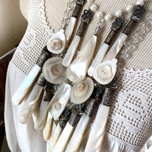 Lyxigt halsband med pärlemorhandtag, manikyrset med antika vintage-snidade repoussé-hylsor, uttalande middagsknappar med flera strängar