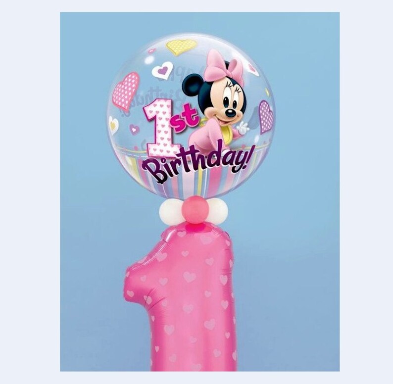 May include: A pink number one balloon with heart patterns, topped with a clear balloon featuring Minnie Mouse and the text "1st Birthday!". The clear balloon has heart and star accents, with a pink bow on Minnie's head.