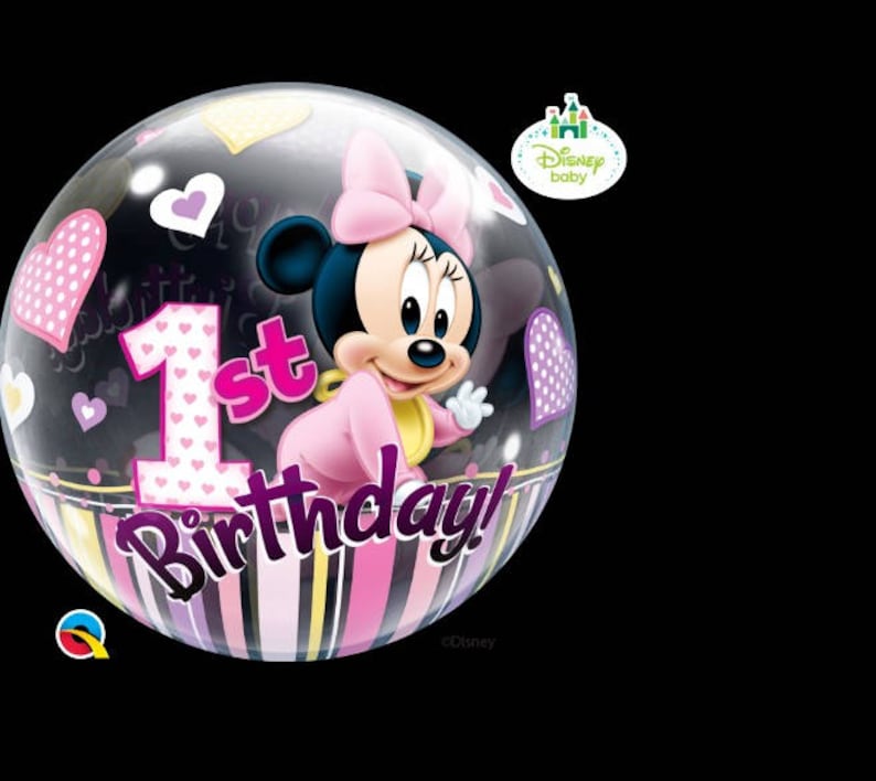 May include: A clear bubble balloon featuring Minnie Mouse in a pink outfit, with the text "1st Birthday!" in pink and purple. The balloon has heart and star decorations, and a striped bottom. A Disney Baby logo is visible.