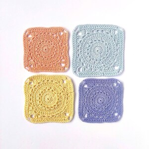 Op de afbeelding: Vier vierkante gehaakte onderzetters in pastelkleuren: perzik, lichtblauw, geel en lavendel. Elke onderzetter heeft een spiraalvormig ontwerp in het midden en een vierkante vorm met afgeronde hoeken. Handgemaakt, geschikt voor woondecoratie.