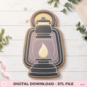 May include: A lantern-shaped biscuit decorated with dark grey icing for the frame, a light purple centre, and a cream-coloured flame design in the middle. The biscuit features white piped outlines and is labelled with the text DIGITAL DOWNLOAD - STL FILE.