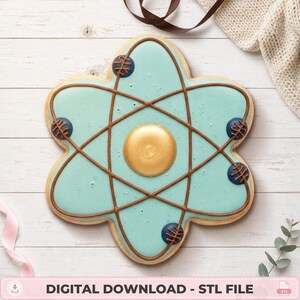 May include: A cookie-shaped atom model featuring a light blue base, a central gold sphere, and dark blue orbiting spheres connected by brown icing lines. The design includes the text DIGITAL DOWNLOAD - STL FILE at the bottom of the image.