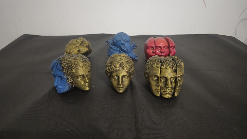 Pode incluir: Uma cole&ccedil;&atilde;o de seis pequenas cabe&ccedil;as esculturais com v&aacute;rios designs. Algumas t&ecirc;m um acabamento em ouro met&aacute;lico, enquanto outras incorporam detalhes em azul ou vermelho. As esculturas exibem tra&ccedil;os faciais e texturas de cabelo detalhados.