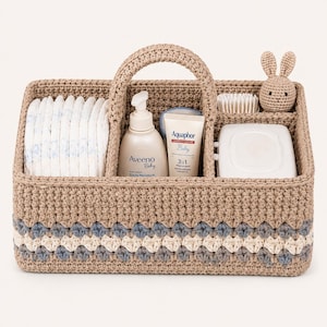 Può includere: Cesta per neonati all'uncinetto color beige con un motivo a conchiglia blu e bianco. Contiene pannolini, lozione per bambini, crema, salviette, una spazzola e un piccolo coniglietto all'uncinetto. Con manico.