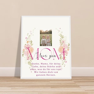 May include: A framed print with a floral wreath design. The word "MOM" is in pink, with "I love you" written above it. A photo of two children is in the center. The print includes German text.