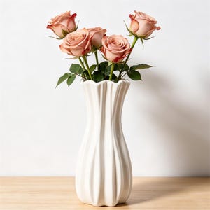Peut inclure: Un vase en céramique blanc cannelé contenant plusieurs roses couleur pêche avec des feuilles vertes. Les roses ont une teinte rouge plus foncée sur les bords de leurs pétales. Le vase est sur une surface en bois clair.