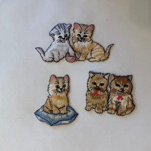 May include: Embroidered patches featuring adorable kittens in various poses. One patch shows two kittens with a ball of yarn, while another depicts a kitten on a blue pillow. The remaining patches show kittens with red bows.