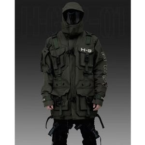 Puede incluir: Chaqueta t&aacute;ctica verde oliva con m&uacute;ltiples bolsillos, correas y hebillas. La chaqueta presenta el texto "H-G" en el pecho y texto en la manga. La chaqueta tiene capucha y cubre la cara. El modelo lleva pantalones negros.