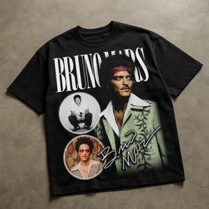 May include: Black t-shirt featuring a vintage-style graphic of Bruno Mars. The design includes the name "BRUNO MARS" in white, along with two circular portraits and a signature. The main image shows Mars in a green jacket and a red headband.