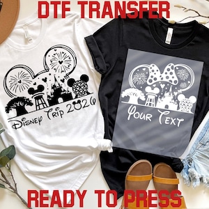 以下が含まれることがあります： ディズニーをテーマにしたデザインの白と黒のTシャツ。白いシャツには「Disney Trip 2026」の文字が入った黒いグラフィックが描かれています。黒いシャツには「Your Text」の文字とミニーマウスのリボンデザインが入ったグレーのオーバーレイがあります。「DTF TRANSFER」と「READY TO PRESS」の文字も表示されています。