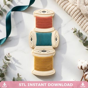 Può includere: Un oggetto decorativo a forma di tre rocchetti di filo impilati color crema, con un rocchetto superiore con filo color corallo, un rocchetto centrale orizzontale con filo verde acqua e un rocchetto inferiore con filo giallo, tutti rigati.