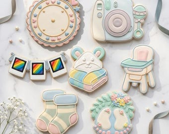 May include: Assortment of baby-themed cookies, including a camera, rattle, high chair, socks, and a wreath with footprints. The cookies are decorated with pastel colors and intricate details. The image also includes a banner with rainbow-colored squares.