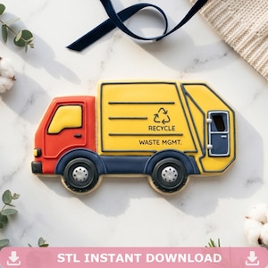 Puede incluir: Una galleta con forma de camión de basura amarillo y rojo con el texto "RECYCLE WASTE MGMT." El camión tiene ruedas negras y un chasis azul. La imagen también incluye el texto "STL INSTANT DOWNLOAD."