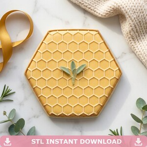 May include: A hexagonal biscuit decorated with a honeycomb design and a small sprig of green leaves. The biscuit is a light yellow colour with a darker border. The text "STL INSTANT DOWNLOAD" is at the bottom of the image.