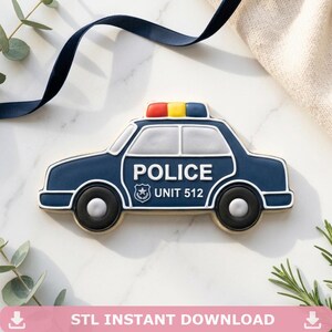 Puede incluir: Una galleta con forma de coche de policía azul marino con detalles en blanco y gris. La galleta tiene ruedas negras y una barra de luces roja, amarilla y azul. La palabra "POLICE" y "UNIT 512" se muestran en el lateral.