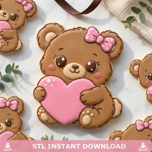 Può includere: Biscotti a forma di orso marrone con dettagli a cuore e fiocco rosa. I biscotti hanno un design carino con un cuore rosa tenuto tra le braccia dell'orso e un fiocco rosa a pois bianchi. Il testo "STL INSTANT DOWNLOAD" è in basso.