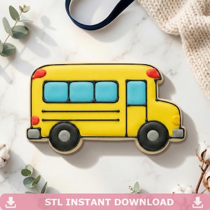Può includere: Un biscotto a forma di scuolabus giallo con ruote nere, finestre blu e luci rosse. Il biscotto è decorato con contorni di glassa nera. Il testo "STL INSTANT DOWNLOAD" è in basso nell'immagine.