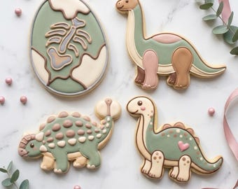 May include: Four dinosaur-themed cookies. One is an egg with a fossil design, and the others are a Brontosaurus, an Ankylosaurus, and a dinosaur with a heart. The cookies are decorated with green, tan, pink, and brown icing. The text "STL INSTANT DOWNLOAD" is at the bottom.