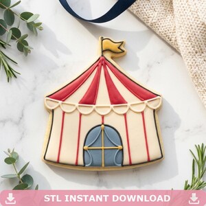 Op de afbeelding: Een koekje in de vorm van een circustent met een rood-wit gestreept dak, een blauwe deur en een gele vlag. De koek heeft een beige basis en zwarte contouren. De tekst "STL INSTANT DOWNLOAD" staat onderaan.