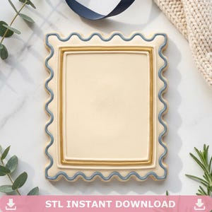 May include: A rectangular, cream-colored frame with a scalloped edge, outlined in blue and gold. The frame has a blank center and the text "STL INSTANT DOWNLOAD" at the bottom. Decorative elements include a navy ribbon and greenery.