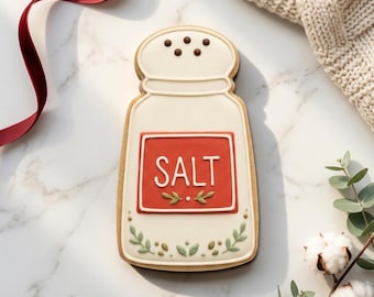 May include: A salt shaker-shaped cookie with white icing and a red rectangle that reads "SALT". The cookie is decorated with green leaves and brown dots. The text "STL INSTANT DOWNLOAD" is at the bottom.