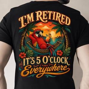May include: A black t-shirt featuring a graphic of a red parrot wearing sunglasses, relaxing in a hammock between two palm trees. The parrot holds a tropical drink. Text reads I'M RETIRED IT'S 5 O'CLOCK EVERYWHERE with a sunset ocean background.