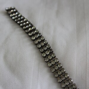 May include: A silver bracelet with a double row of clear rhinestones.