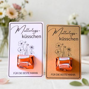Pode incluir: Dois cartões com um chocolate Ferrero Rocher anexado. Um cartão é branco com texto preto e uma ilustração floral, o outro é marrom. O texto nos cartões diz "Muttertagsküsschen" e "Für die beste Mama."