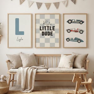 Op de afbeelding: Drie ingelijste wandkunstprints. Eén heeft de blauwe letter "L" met een naam eronder, een andere heeft een dambordpatroon met de tekst "Little Dude", en de derde toont drie vintage raceauto's. De prints zitten in houten frames.