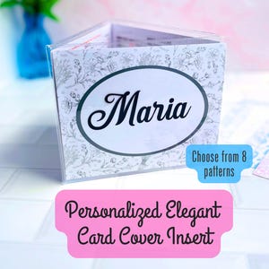 May include: A clear plastic card holder featuring a white insert with a black floral line drawing pattern. The center of the insert displays the name Maria in a black script font inside a dark oval frame. Text on the image reads Choose from 8 patterns.