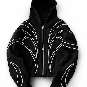 May include: Black zip-up hoodie with a hood and white abstract design. The hoodie features a full-length zipper and white curved lines on the front and sleeves. The hoodie is made of a soft material.
