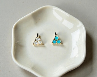 May include: Two gold-tone stud earrings, each featuring a triangular cluster of three small stones. One earring contains clear, faceted white stones, while the other earring contains three round, opaque turquoise-colored stones set in gold metal.