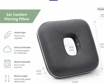 May include: A square dark gray ear comfort piercing pillow with a central circular cutout. The pillow measures 9.8 inches by 9.8 inches with a 2.3-inch thickness and a 3.5-inch center hole. Text on the image reads Ear Comfort Piercing Pillow.